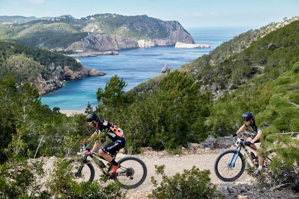 Twee mountainbikers op een trail op Ibiza met uitzicht op de baai – begeleide MTB tour met Bike Ibiza