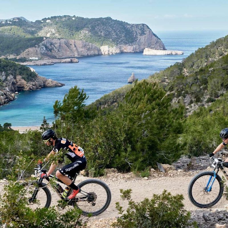 Twee mountainbikers op een trail op Ibiza met uitzicht op de baai – begeleide MTB tour met Bike Ibiza