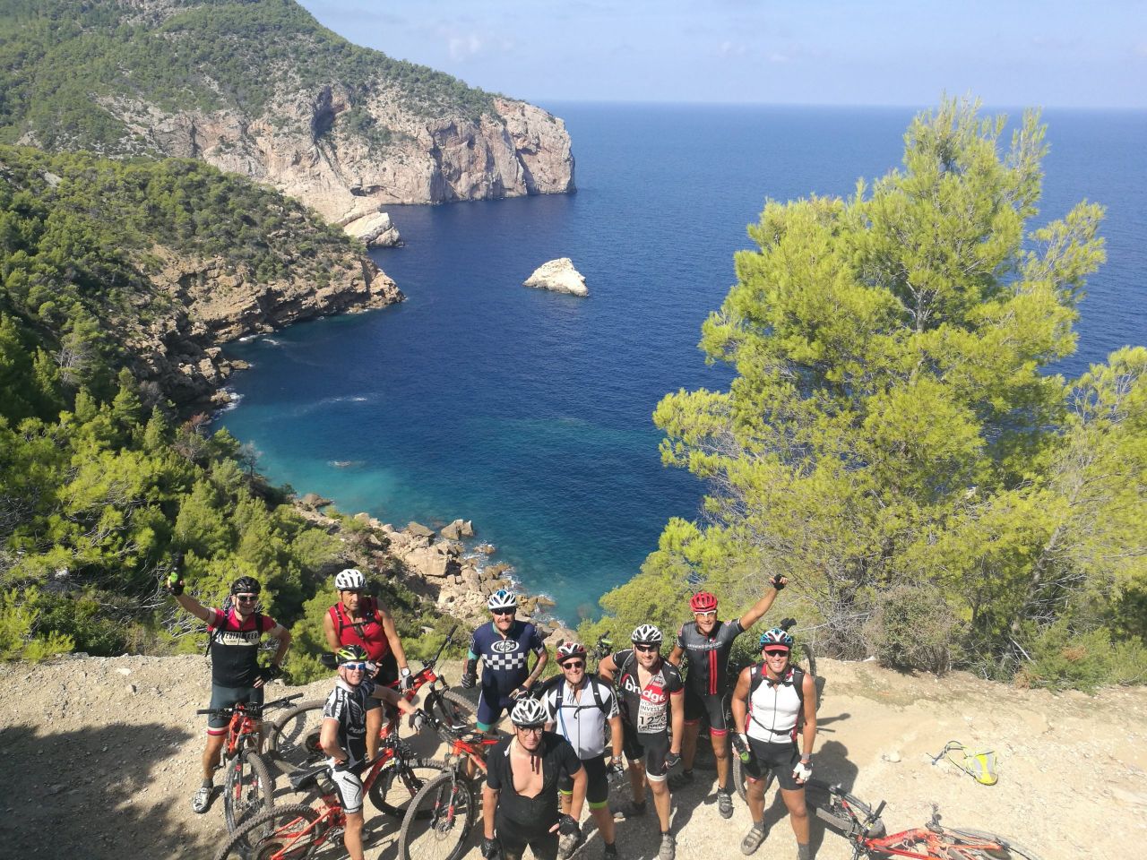 Grupo de ciclistas de montaña en un mirador sobre la costa de Ibiza